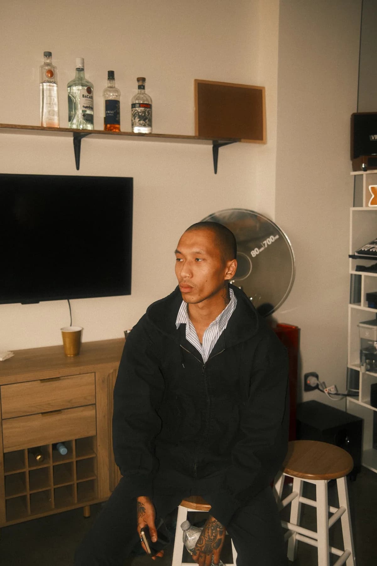 A guest with tattooed hands sitting on a stool at OTL Sessions vol. 1, a giant CD clock behind him.